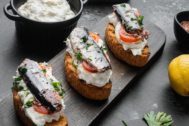 Set di toast alla ricotta e sardine, su sfondo nero tavolo in pietra scura