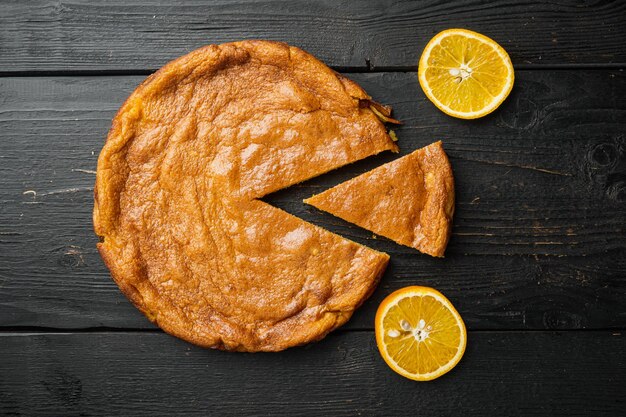 Set di torta di polenta all'arancia, su sfondo di tavolo in legno nero, vista dall'alto piatta