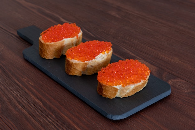 Set di tre panini con caviale rosso sul bordo di pietra grigia