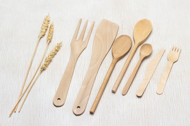 Set di utensili da cucina in legno Cucchiai forchette spatola e rametti di grano Vista dall'alto Sfondo bianco
