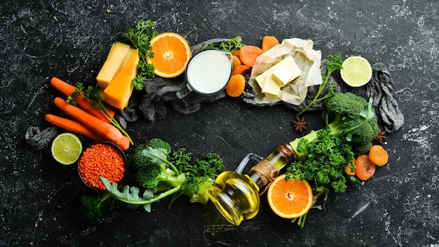 Set di verdure, frutta e cibo su uno sfondo di pietra nera Gli alimenti sono ricchi di vitamina A Vista dall'alto Spazio libero per il testo