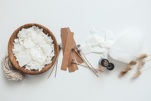 Set per la lavorazione di candele su sfondo bianco Cera di soia ecologica e strumenti per la produzione di candele vista dall'alto candele piatte fai da te Concetto di hobby