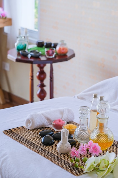 Set per trattamenti spa e olio da massaggio aromatico sul massaggio del letto. Ambiente tailandese per aromaterapia e massaggio con fiori sul letto, relax e cure salutari.