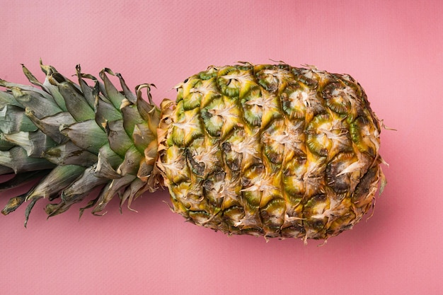 Set singolo ananas intero, su sfondo estivo strutturato rosa, vista dall'alto piatta