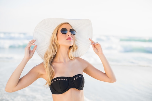 Sexy bionda in bikini elegante indossando cappello di paglia e occhiali da sole