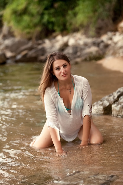 Sexy donna bruna in ginocchio sulla spiaggia del mare