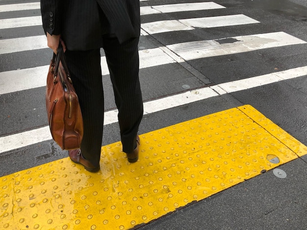 Sezione bassa dell'uomo che attraversa la strada