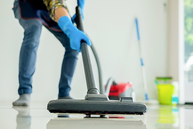 Sezione bassa dell'uomo che pulisce il pavimento con l'aspirapolvere a casa