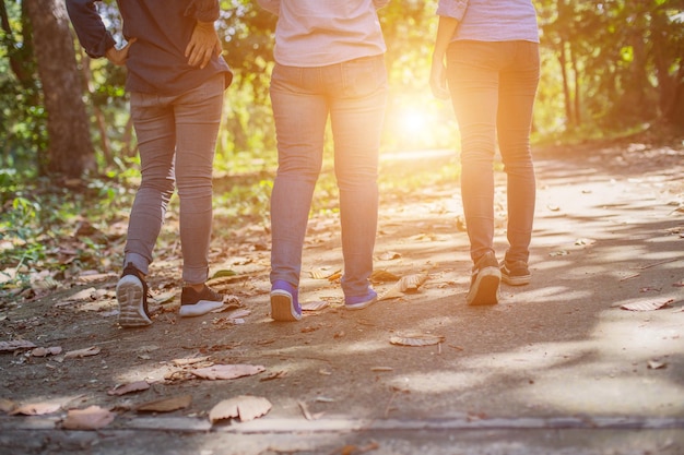 Sezione bassa di amici che camminano sulla strada durante una giornata di sole