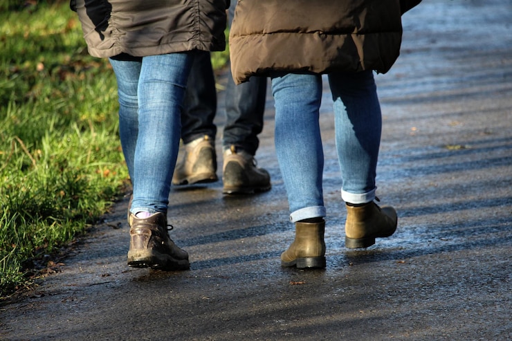 Foto sezione bassa di persone che camminano su una strada bagnata