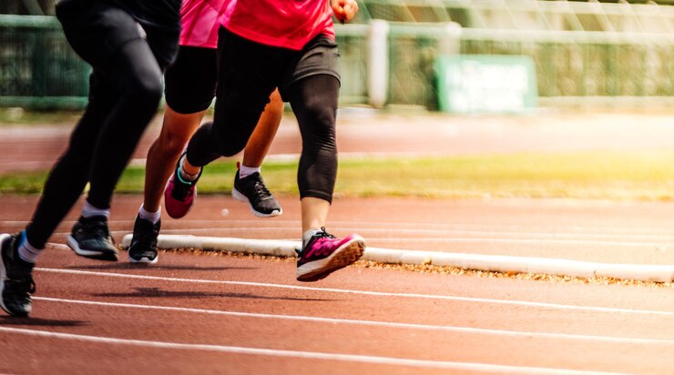 Foto sezione bassa di persone che corrono su una pista sportiva