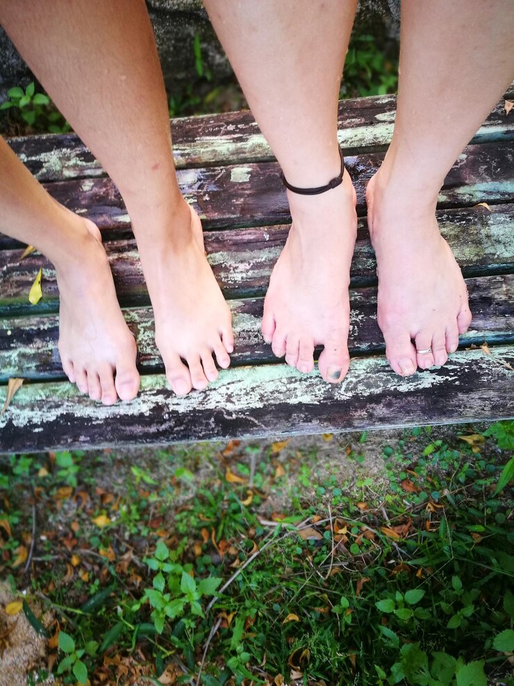 Foto sezione bassa di persone in piedi su una panchina di legno