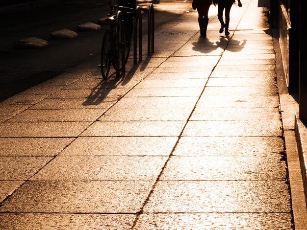 Sezione bassa di silhouette di persone che camminano per strada