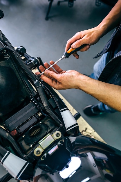 Sezione bassa di un meccanico maturo che ripara una moto in garage