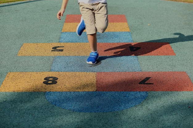 Sezione bassa di un ragazzo che gioca a hopscotch
