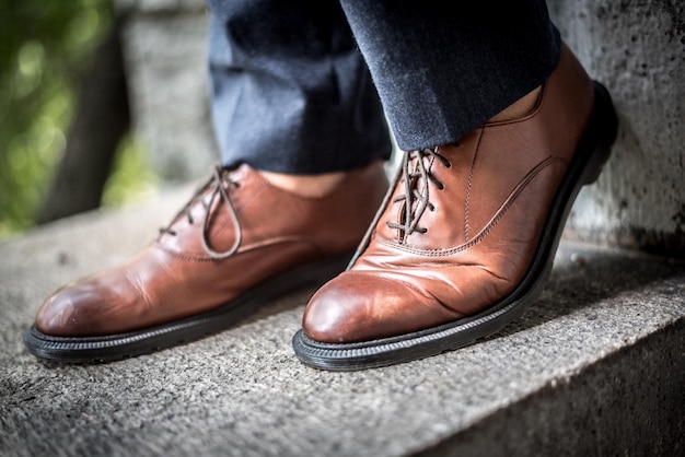 Sezione bassa di un uomo che indossa scarpe marroni sul muro di sostegno