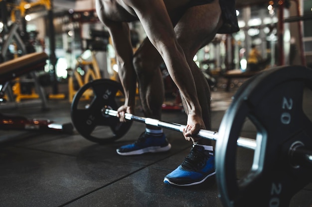Sezione bassa di un uomo che solleva un barbell in palestra