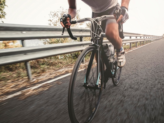 Sezione bassa di un uomo che va in bicicletta sulla strada con la ringhiera