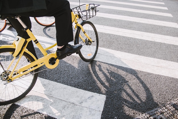 Sezione bassa di un uomo con una bicicletta che attraversa la strada