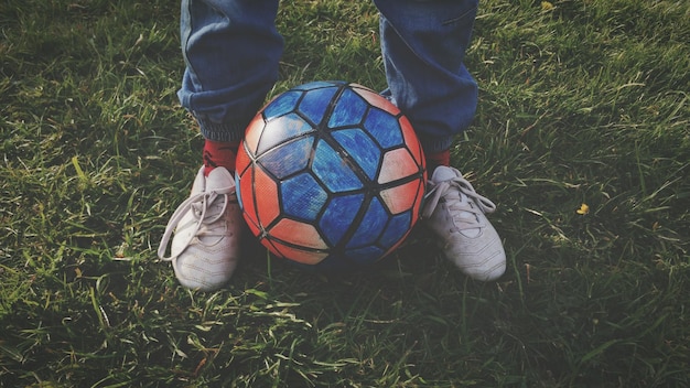 Sezione bassa di un uomo con una palla da calcio su un campo erboso