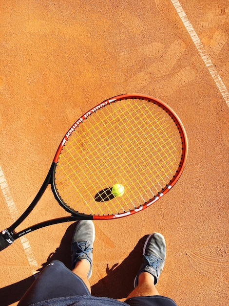 Sezione bassa di un uomo in piedi al campo da tennis