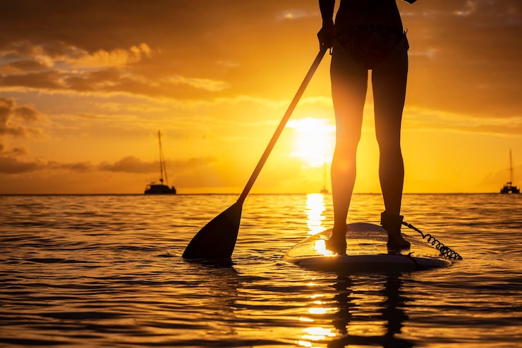 Foto sezione bassa di un uomo in piedi in mare contro il cielo durante il tramonto