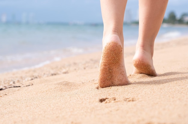 Sezione bassa di una donna che cammina sulla sabbia sulla spiaggia
