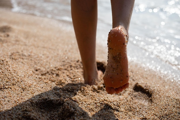 Sezione bassa di una donna in piedi sulla sabbia sulla spiaggia