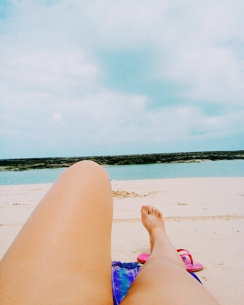 Sezione bassa di una donna sulla spiaggia contro il cielo