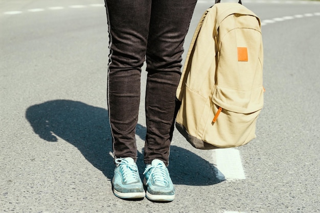 Sezione bassa di una persona con una borsa in piedi sulla strada