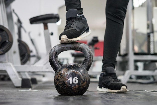 Sezione bassa di una persona in piedi su un kettlebell in palestra