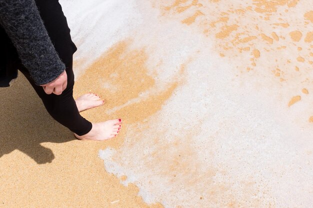 Sezione bassa di una persona sulla sabbia in spiaggia