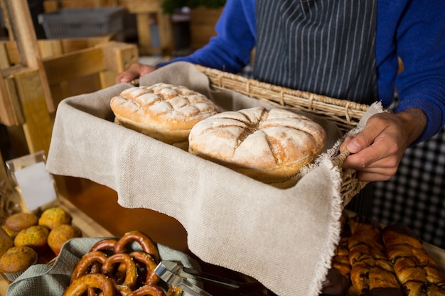 Sezione centrale del personale che tiene un cesto di vimini di pane al banco