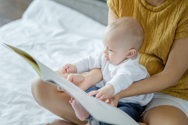 Sezione centrale della madre seduta con il bambino che tiene un libro sul letto a casa