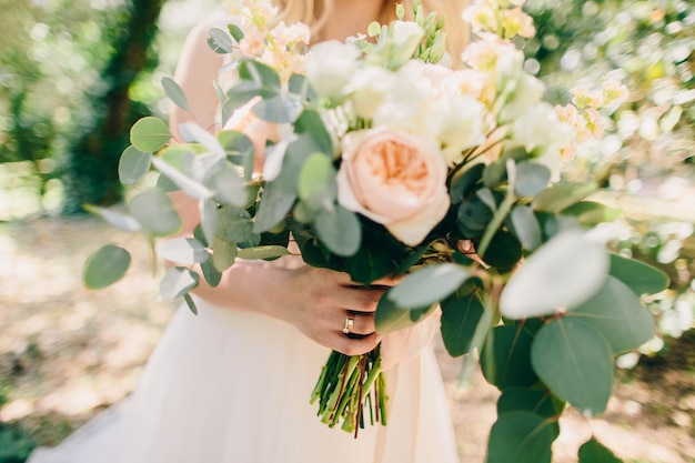 Sezione centrale della sposa che tiene un bouquet di fiori