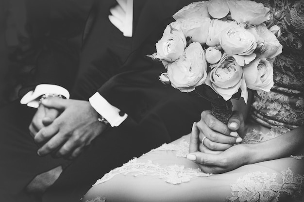Sezione centrale della sposa che tiene un bouquet mentre è seduta accanto allo sposo