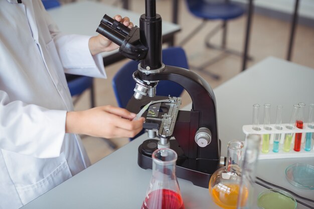 Sezione centrale della studentessa che sperimenta sul microscopio in laboratorio