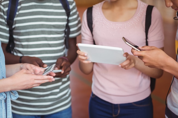 Sezione centrale di studenti che utilizzano telefoni cellulari e tablet digitali nel campus