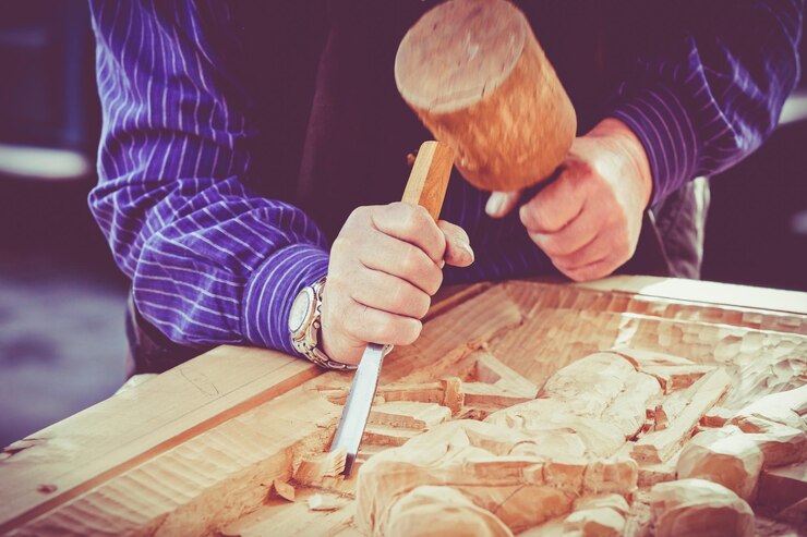 Foto sezione centrale di un artigiano che scolpisce il legno nel laboratorio