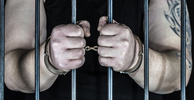 Sezione centrale di un criminale dietro le sbarre di sicurezza in prigione