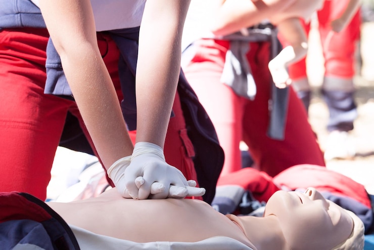 Foto sezione centrale di un paramedico che esegue la rianimazione cardiopulmonare su un manichino all'aperto