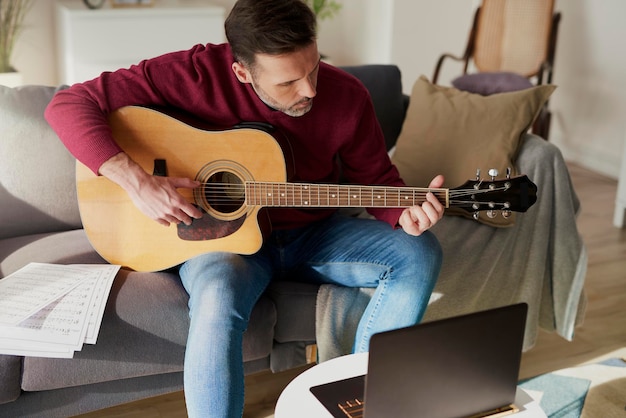 Sezione centrale di un uomo che suona la chitarra a casa
