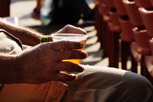 Sezione centrale di un uomo che tiene l'alcol mentre è seduto all'aperto