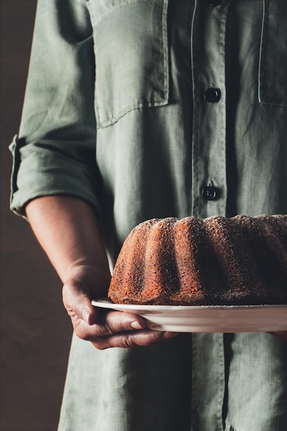Sezione centrale di un uomo che tiene una torta di bundt in un piatto