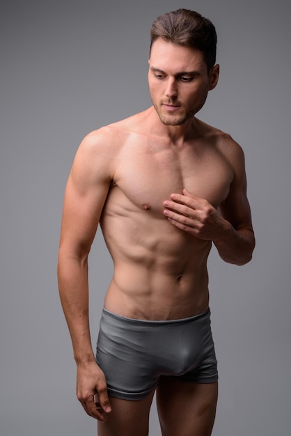 Sezione centrale di un uomo senza camicia in piedi sullo sfondo grigio