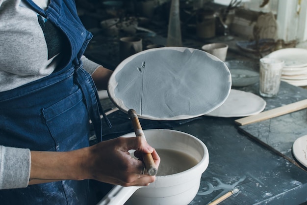 Sezione centrale di una donna che fa un prodotto d'arte in argilla in un laboratorio