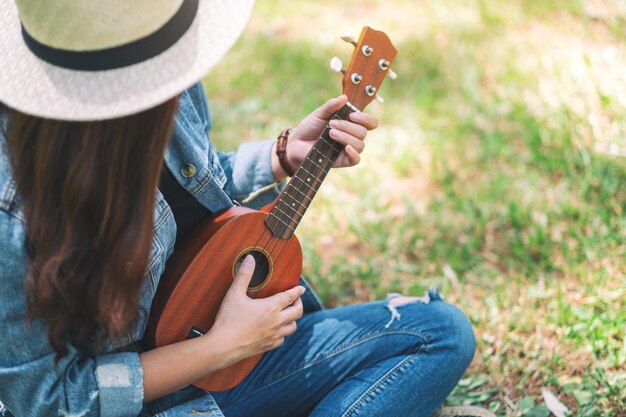 Sezione centrale di una donna che suona l'ukelele seduta sull'erba