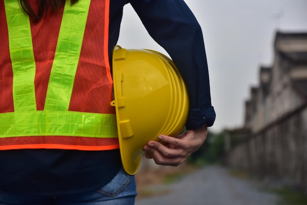 Sezione centrale di una donna che tiene il cappello mentre è in piedi sul cantiere