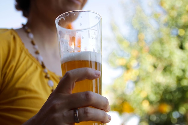 Sezione centrale di una donna che tiene la birra nel cortile sul retro