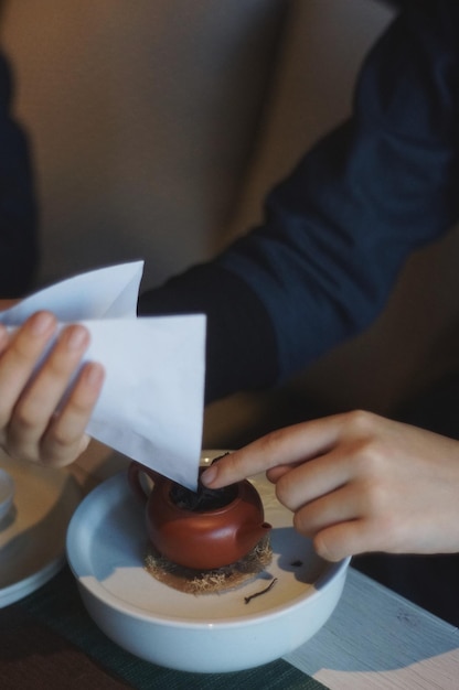 Sezione centrale di una donna che tiene la carta con le foglie di tè al tavolo